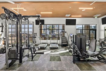 A gym with a variety of equipment including a treadmill, weights, and a bench press.